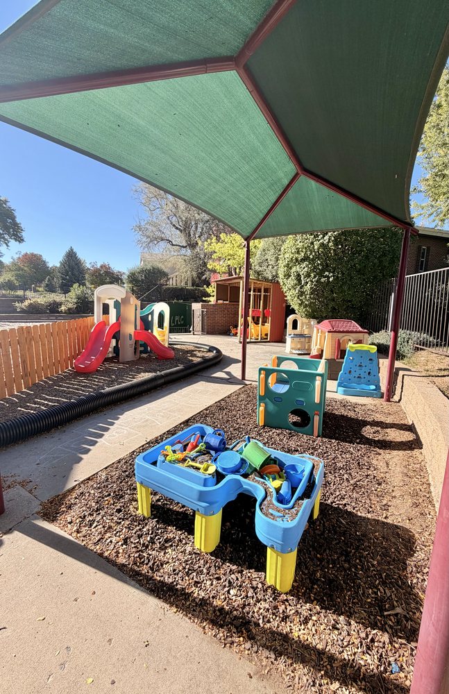 A sand and water table under a shade canopy on the playground